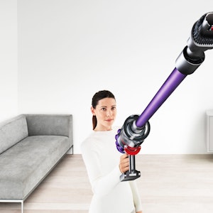 Eine Frau saugt die Wohnung mit einem kabellosen Dyson V11 Absolute Extra Pro Staubsauger.
