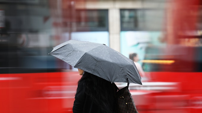 Eine Frau steht am Morgen (4. Juni 2020) mit einem Regenschirm an einer Straßenbahnhaltestelle. Regen bestimmt kurz vor dem Wochenende das Wetter in Nordrhein-Westfalen.