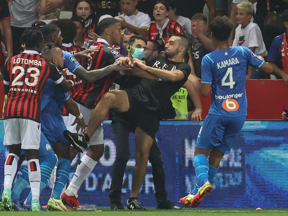 Spieler von Nizza und Marseille versuchen einen Fan am Platzsturm zu hindern.