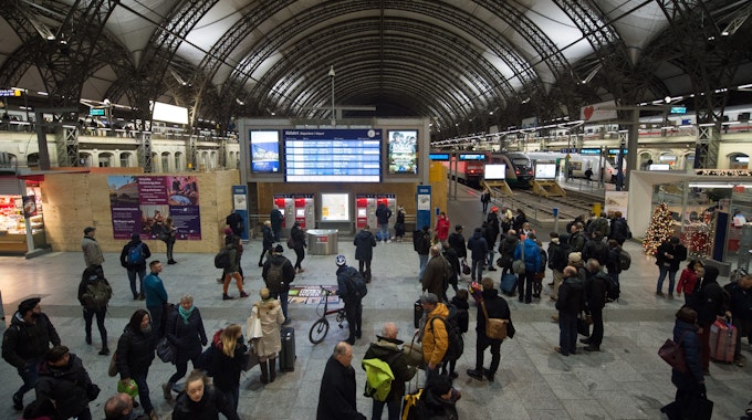 Zugreisende stehen im Dezember 2018 im Dresdner Hauptbahnhof vor einer Anzeigetafel.