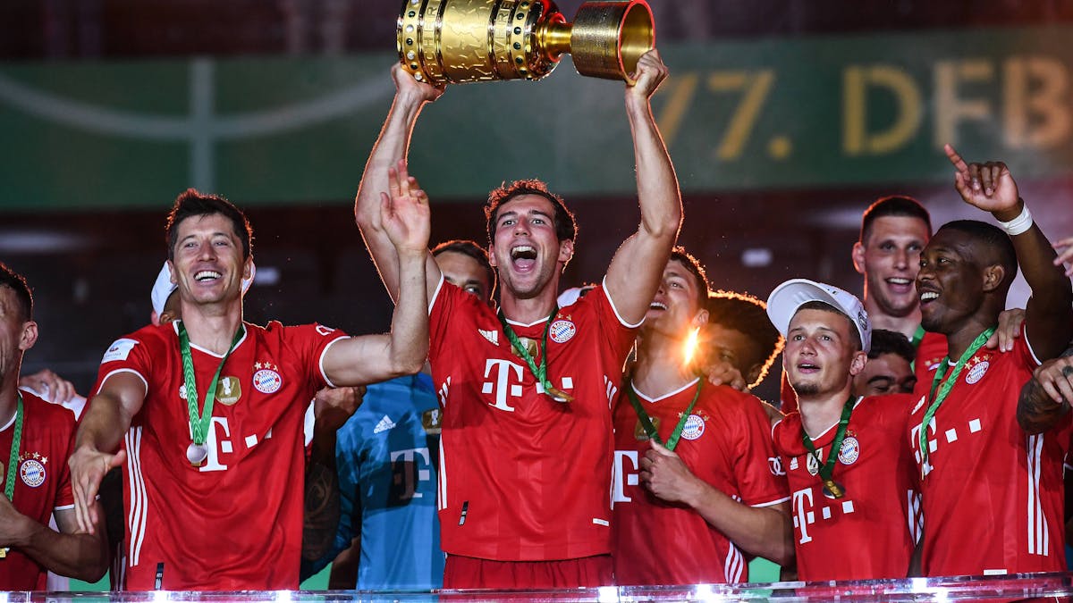 Leon Goretzka hält den DFB-Pokal mit seinen Händen in den Nachthimmel, neben ihm feiert Robert Lewandowski.