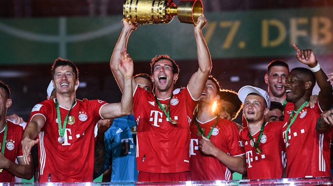 Leon Goretzka hält den DFB-Pokal mit seinen Händen in den Nachthimmel, neben ihm feiert Robert Lewandowski.