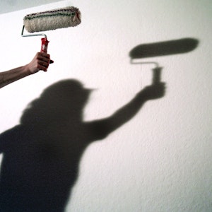 Der Schatten einer Frau mit einer Anstreicherrolle zeichnet sich an einer Wand ab, aufgenommen im Dezember 2003