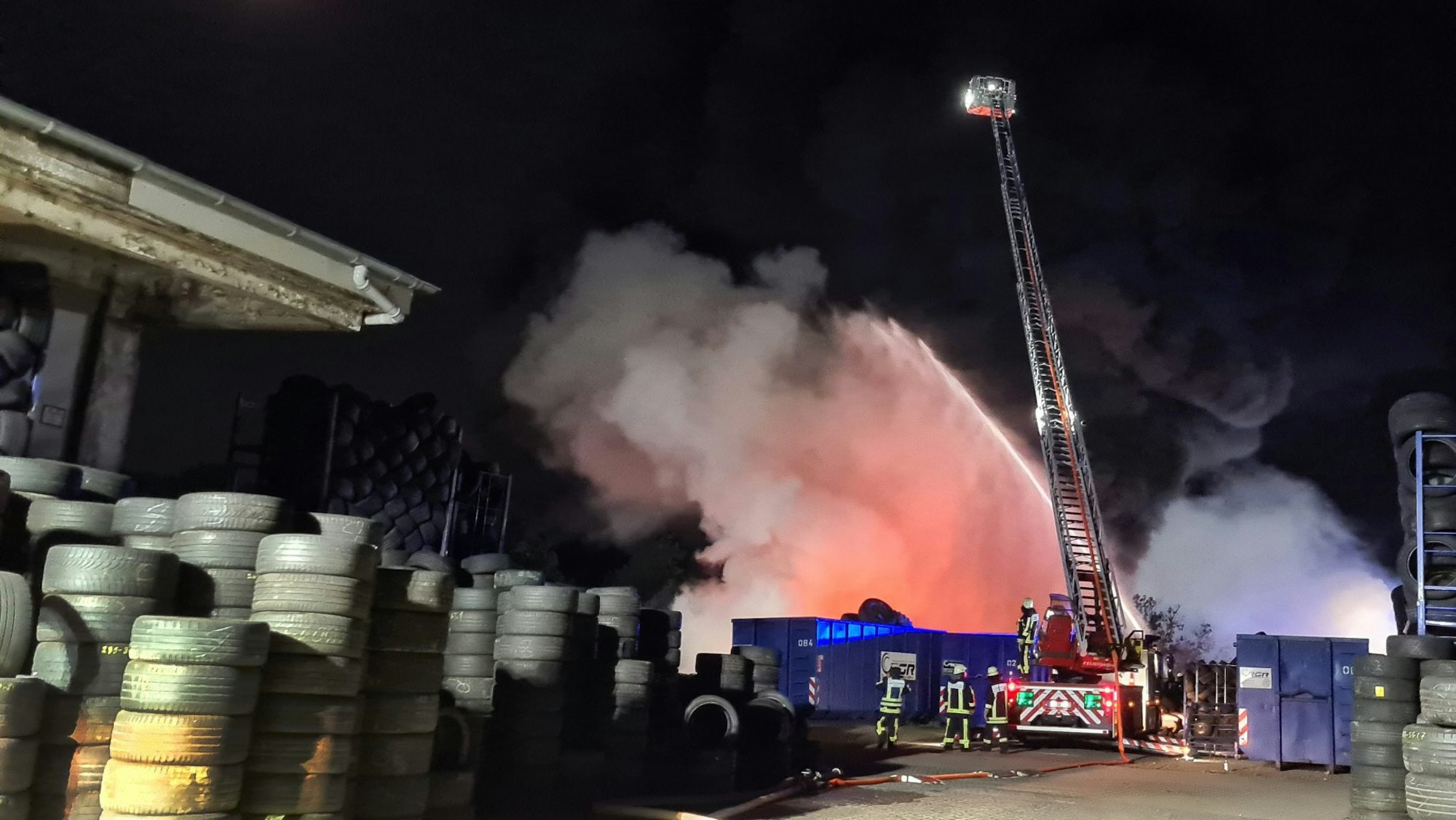 Feuerwehrleute löschen am 24.08.2021 von einer Drehleiter aus einen Brand in einem Reifenlager in Bochum.