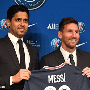 Lionel Messi und PSG-Präsident Nasser Al-Khelaifi halten ein PSG-Trikot hoch.