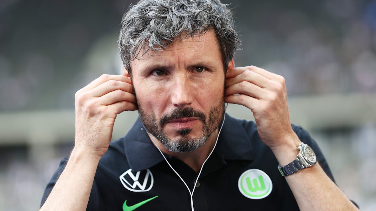Wolfsburgs Trainer Mark van Bommel setzt Kopfhörer vor einem Interview auf.
