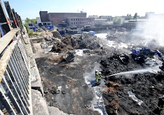 Nach dem Brand in einem Bochumer Reifenlager löschen Feuerwehrleute noch die letzten Brandnester.
