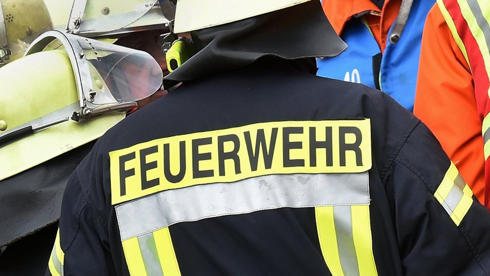 Der Schriftzug Feuerwehr steht während einer Rettungs-Übung an der Jacke eines Feuerwehrmannes.