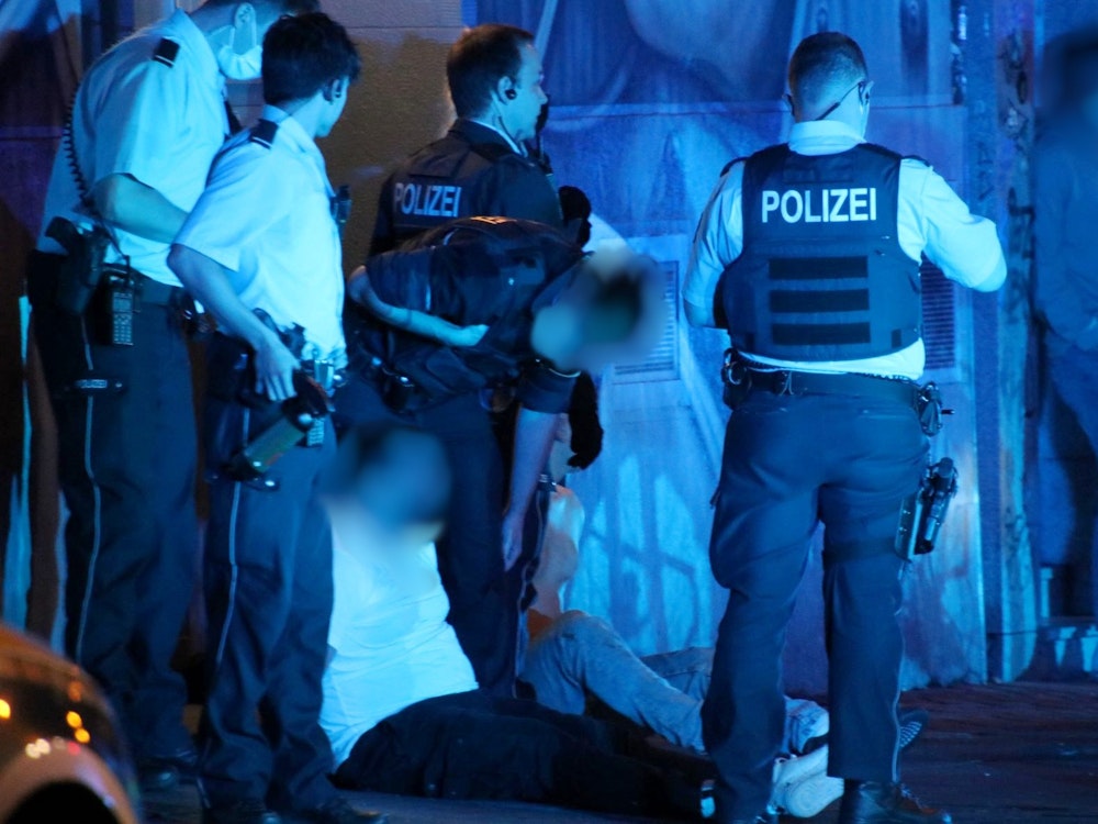 Polizisten stehen nachts am Zülpicher Platz und haben zwei Männer festgenommen.