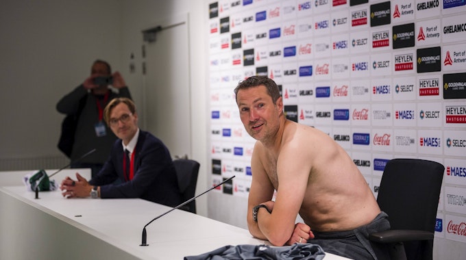 Brian Priske spricht mit nacktem Oberkörper auf der Pressekonferenz von Royal Antwerpen.