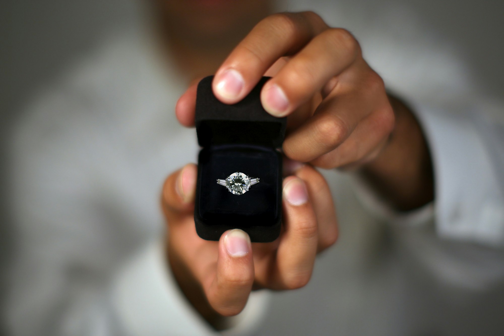 Ein Mann hält eine Ringschachtel mit einem Diamant-Ring in der Hand.