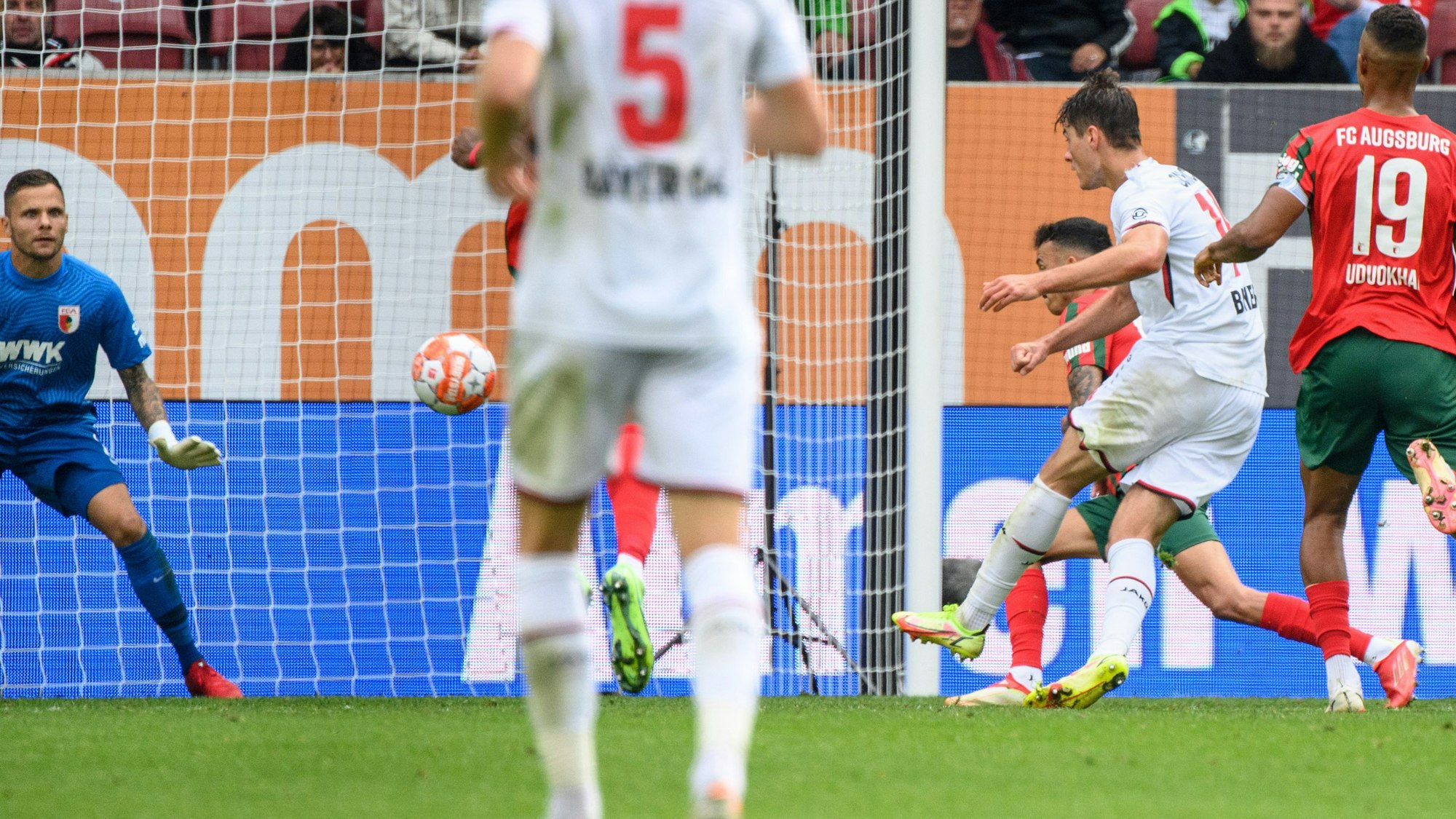 Iago (verdeckt) hebt den Ball im Spiel des FC Augsburg gegen Bayer Leverkusen über den eigenen Torwart.