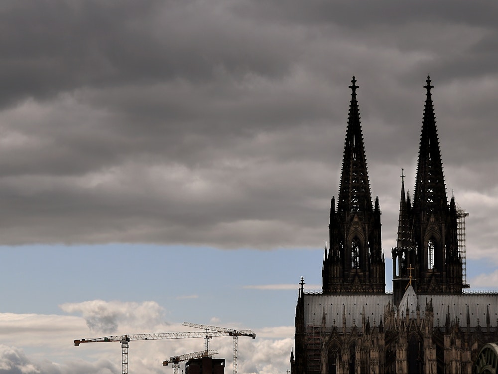 Der Kölner Dom mit seinen Turmspitzen kratzt an den dunklen Wolken.