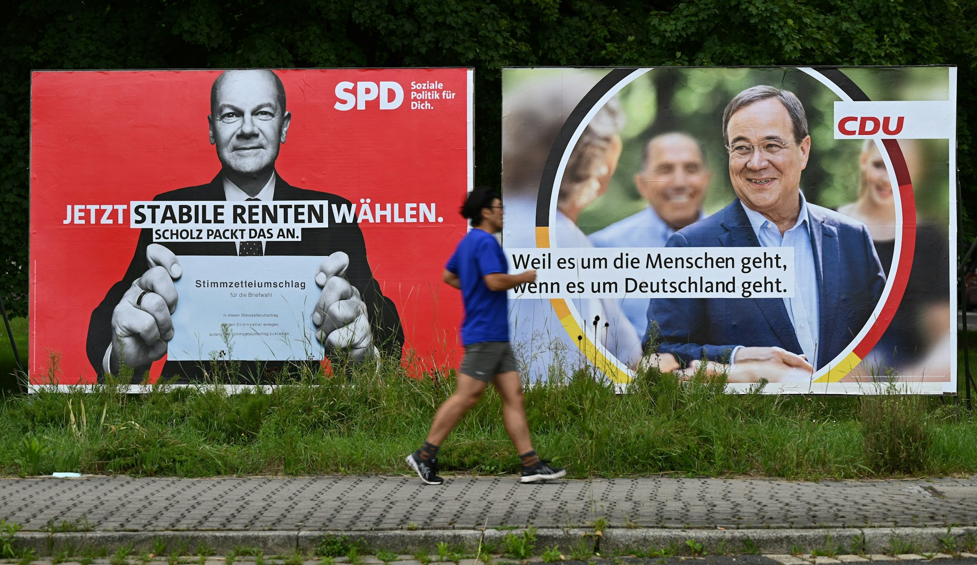 Ein Jogger läuft an großen Wahlplakaten mit den Spitzenkandidaten Olaf Scholz (SPD, l) und Armin Laschet (CDU) vorbei.
