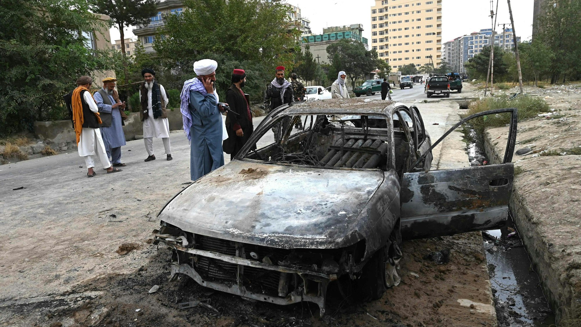 Menschen stehen an einem durch einen Raketenangriff beschädigtes Fahrzeug. In der afghanischen Hauptstadt Kabul hat es einem Medienbericht zufolge einen Raketenangriff gegeben.