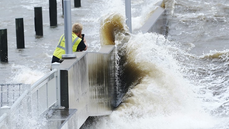 Ein Arbeiter eines Versorgungsunternehmens fotografiert am 29.08.2021 die Wellen, die in Bay Saint Louis, Missouri, gegen eine Ufermauer im städtischen Jachthafen schlagen, während die äußeren Bänder des Hurrikans Ida eintreffen