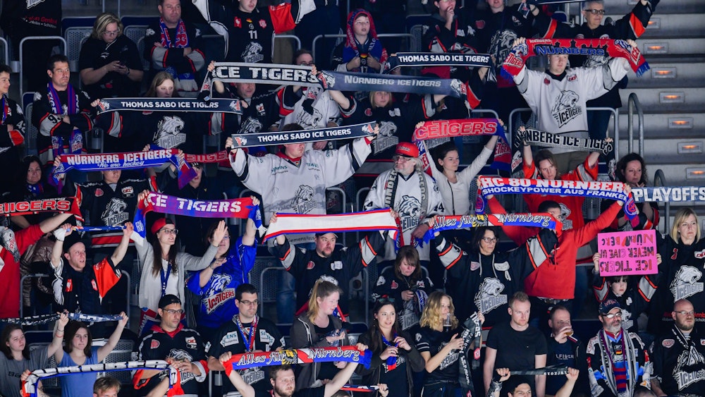 Fans der Nürnberg Ice Tigers halten ihre Schals in die Luft