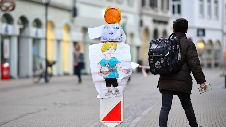 Ein Junge geht am 04.10.2017 in Heidelberg (Baden-Württemberg) in der Hauptstraße an einer Straßenabsperrung mit Absperrband vorbei, an der ein Zettel mit der Aufschrift „Schulweg “angebracht ist.