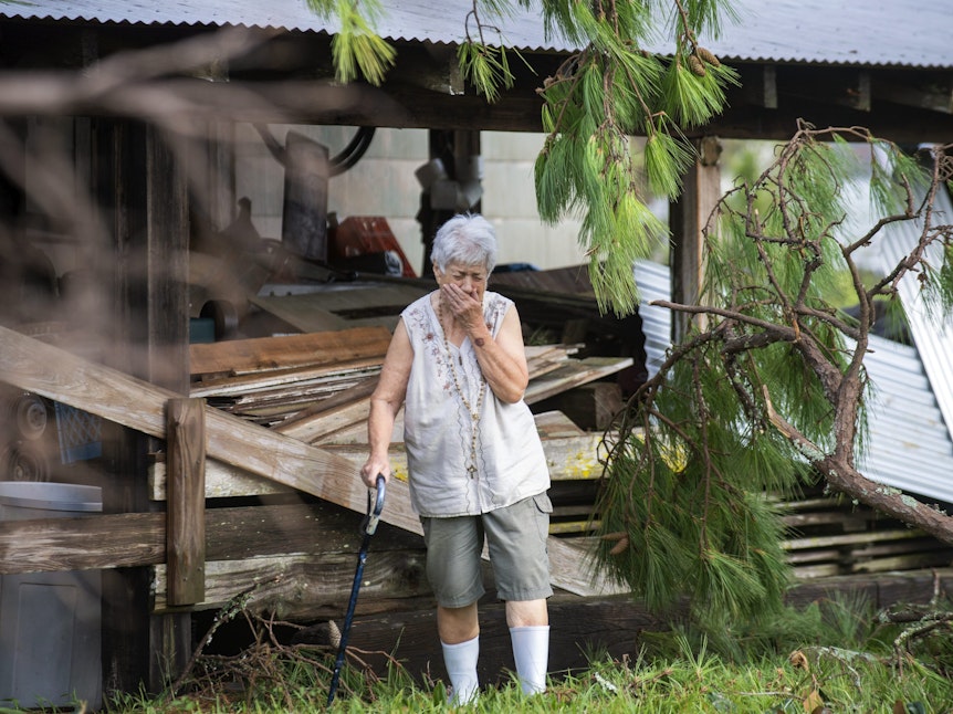 Sharon Orlando steht auf einen Stock gestützt fassungslos vor den Trümmern ihres Hauses und versucht, die Tränen zurückzuhalten.