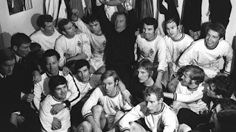 Trainer-Legende Hennes Weisweiler hält, umgeben von seiner Mannschaft, stolz die erste Gladbacher Meisterschale in die Höhe.
