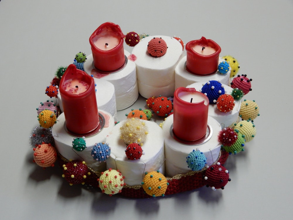 Ein Adventskranz auch acht Klopapierrollen, vier Kerzen und gehäkelten Corona-Viren.