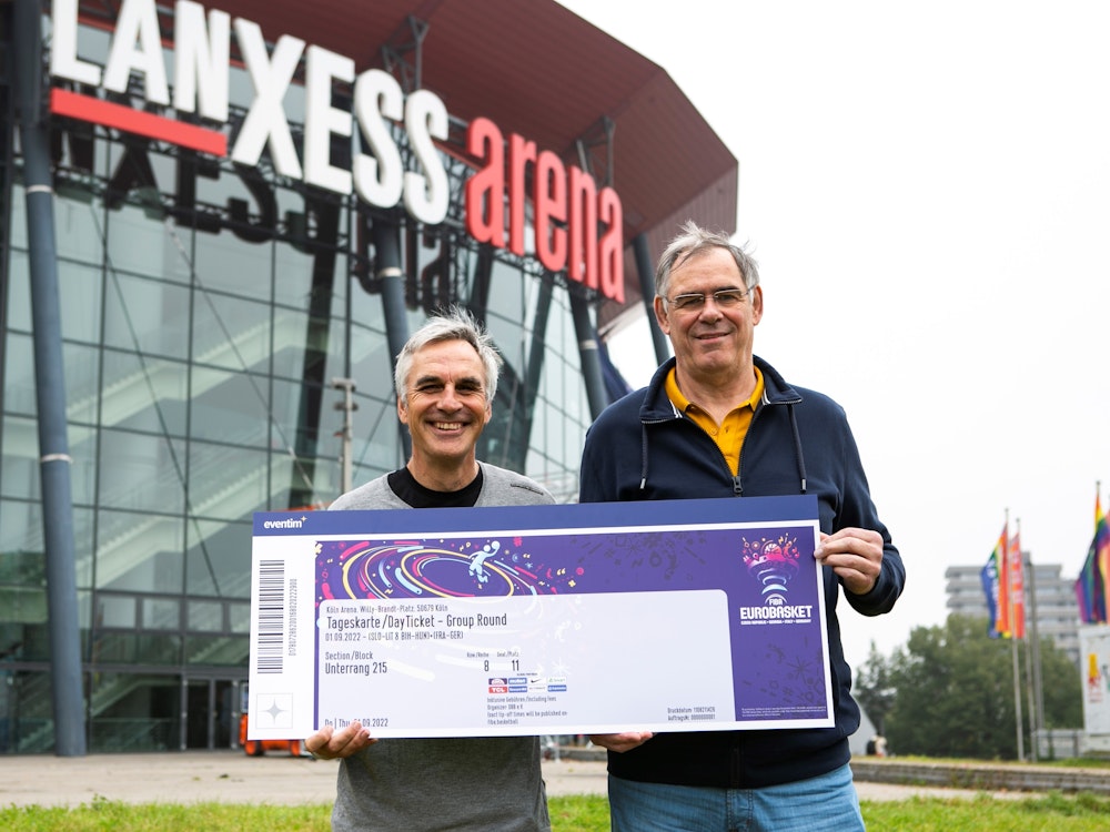 Ein Jahr vor dem Turnierstart: Die Kölner Basketball-Legenden Stefan Baeck und Klaus Zander präsentieren ein symbolisches Ticket für die Basketball-EM 2022 in Köln und Berlin.