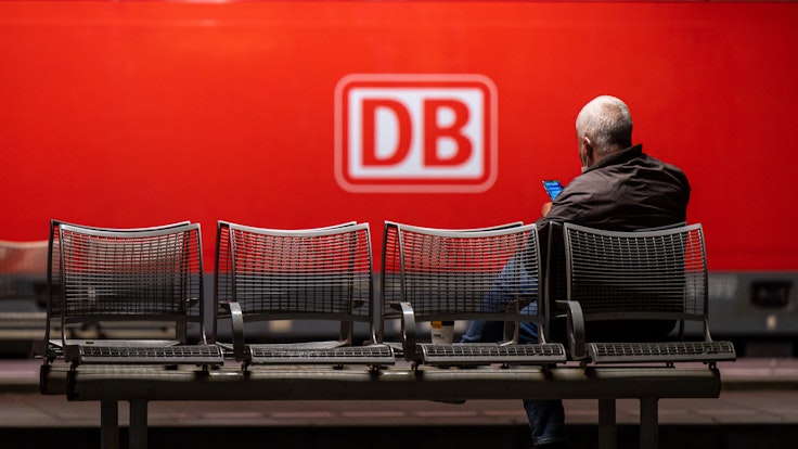 Das Logo der Deutschen Bahn (DB) prangt an der Seite einer Lok, während ein Mann in München am Donnerstag (2. September) auf dem Hauptbahnhof wartet. Die Deutsche Bahn geht gerichtlich gegen den GDL-Streik vor.