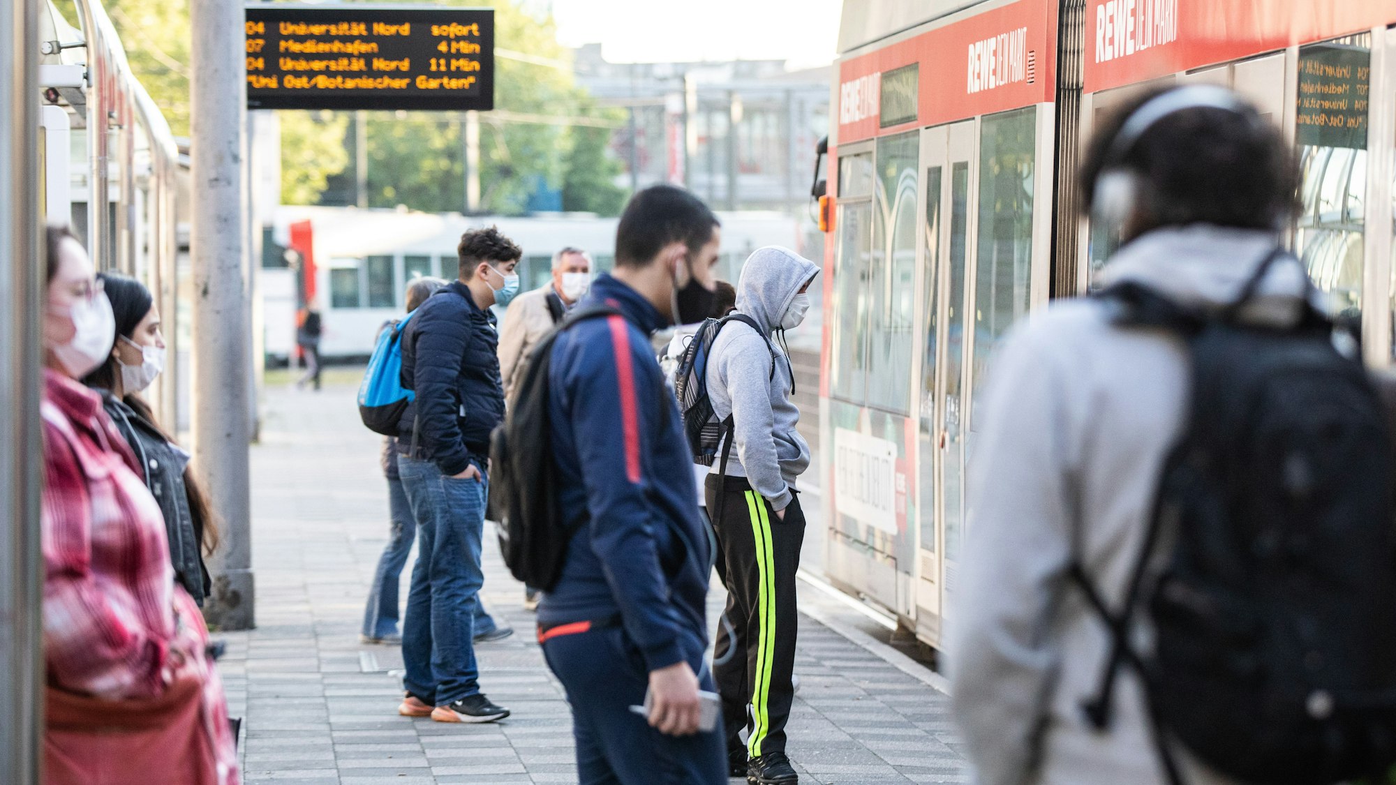Zahlreiche Pendler warten am Morgen mit verschiedenen Gesichtsbedeckungen vor einer Straßenbahn in Düsseldorf (Archivbild vom April 2020): In Düsseldorf wurde ein Mann mit einem regenbogenfarbenen Mund-Nase-Schutz beleidigt und körperlich angegriffen.