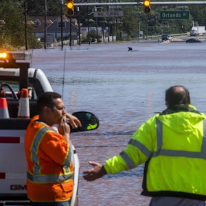 Menschen stehen an der überfluteten Bundesstraße 206 in New Jersey. Im Hintergrund sind überflutete Autos zu sehen.