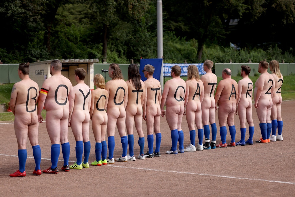 14 nackte Spielerinnen und Spieler drehen ihre Rücken zur Kamera. Sie tragen jeweils einen Buchstaben bzw. eine Ziffer auf dem Rücken. Zu lesen ist: Boycott Qatar 22.