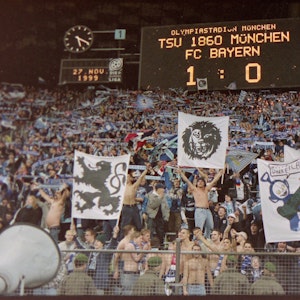 Auf der Anzeigetafel steht, dass 1860 mit 1:0 gegen Bayern gewonnen hat. Darunter freuen sich die Fans der Löwen.