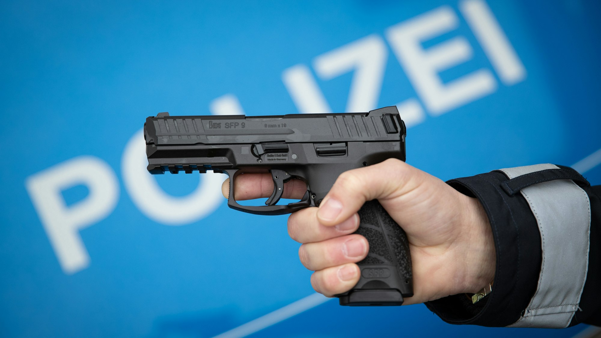 Ein Polizist hält eine Dienstwaffe in der Hand.