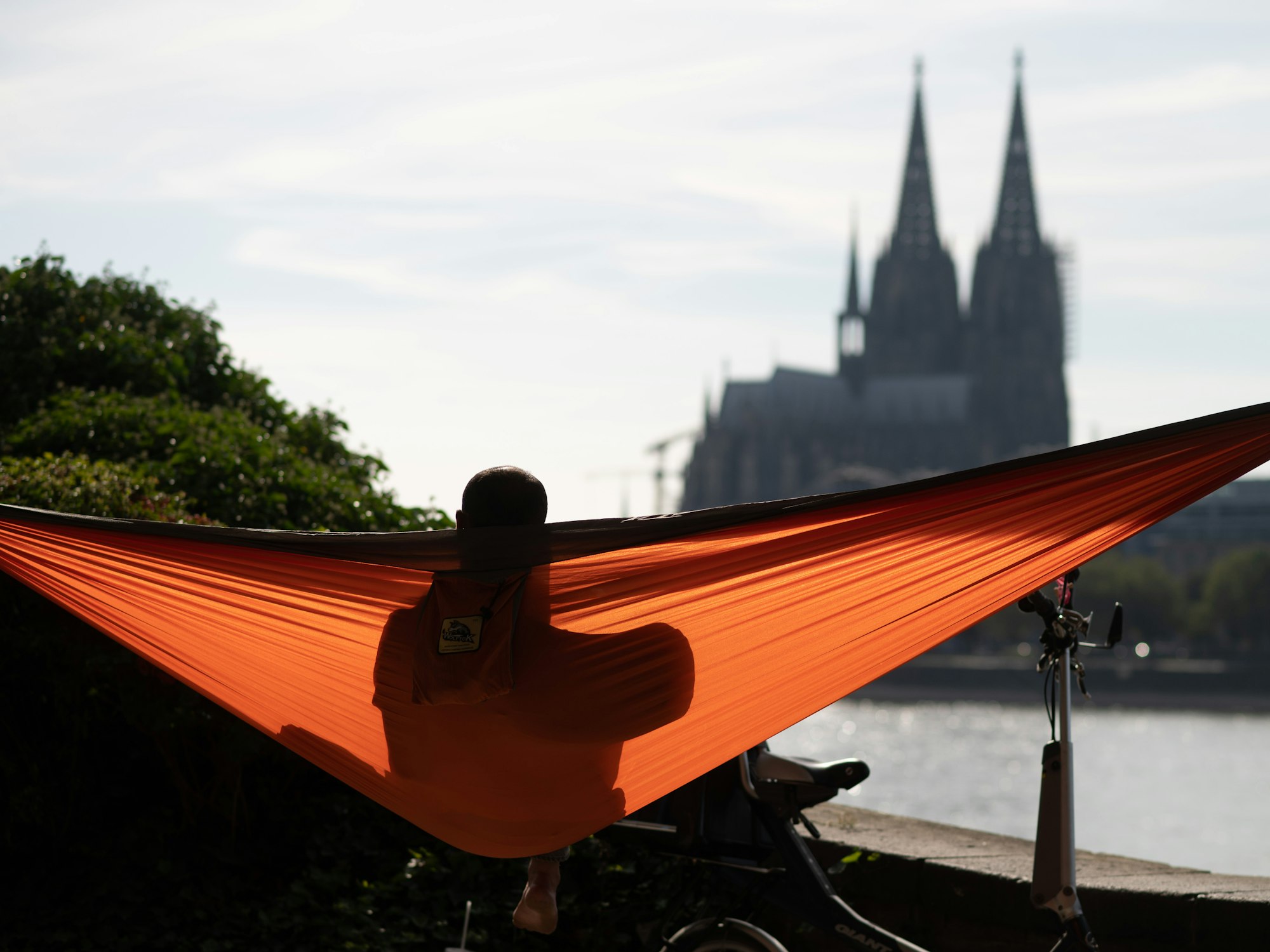 Ein Mann sitzt in einer Hängematte und schaut auf den Kölner Dom.