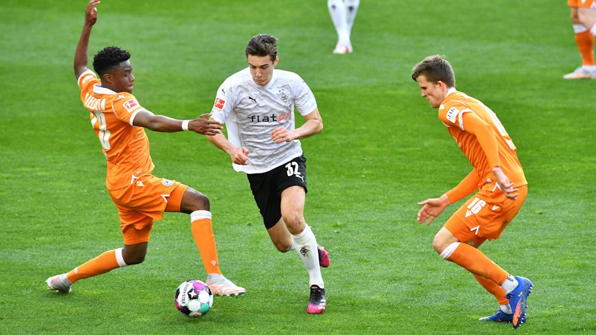 Florian Neuhaus von Borussia Mönchengladbach (Mitte) behauptet den Ball gegen zwei Gegenspieler von Arminia Bielefeld
