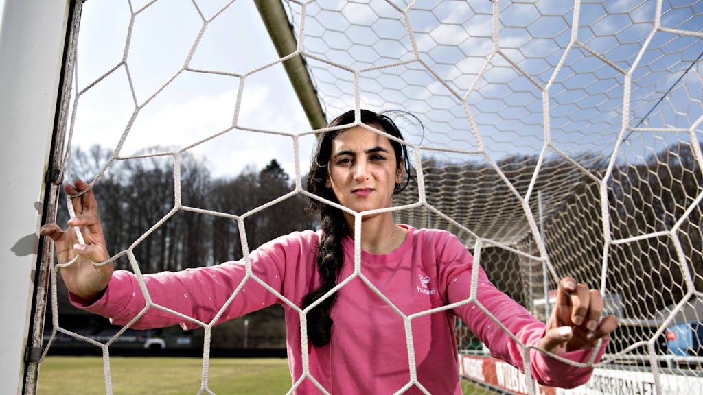 Khalida Popa posiert in einem Tor, sie schaut durch das Tornetz.