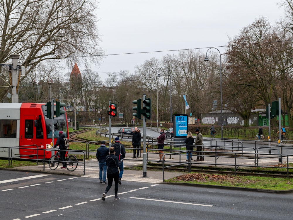 Fußgänger passieren einen Bahnübergang an der Aachener Straße