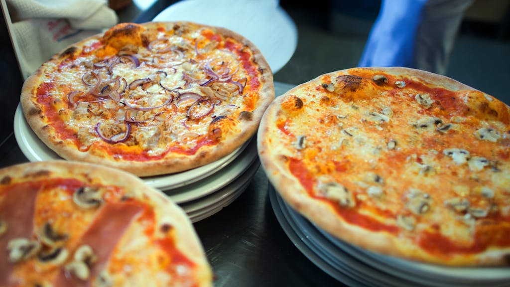 Wer Hunger auf Pizza hat, sollte in NRW bestellen. Das Online-Portal Speisekartenweb.de hat die Preise analysiert. Unser Foto zeigt, wie eine Pizza auf einen Teller geschoben wird.