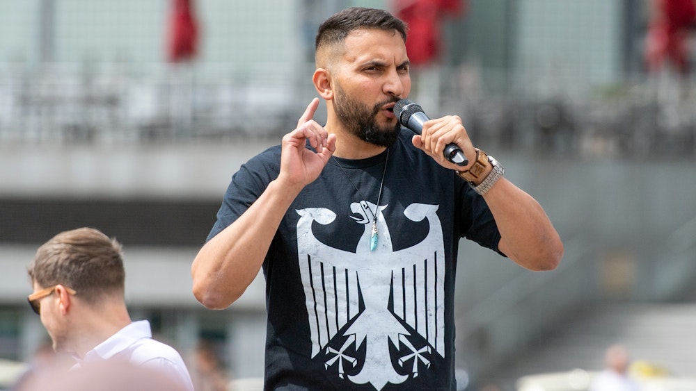 Der Verschwörungsprediger Attila Hildmann spricht im Juli 2020 bei einer Anti-Corona-Demo in Berlin. Er trägt ein schwarzes Shirt mit dem Bundesadler.