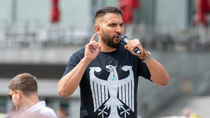 Der Verschwörungsprediger Attila Hildmann spricht im Juli 2020 bei einer Anti-Corona-Demo in Berlin. Er trägt ein schwarzes Shirt mit dem Bundesadler.