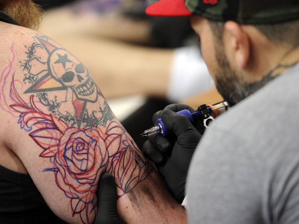 Ein Tätowierer sticht ein Tattoo.