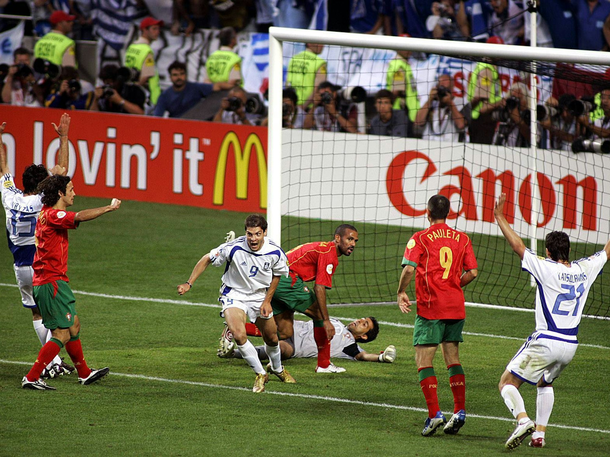 Charisteas setzt nach dem 1:0-Treffer zu seinem Jubellauf an, seine Mitspieler reißen die Arme hoch, die Spieler der Portugiesen sind entsetzt.