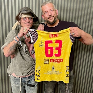 Johnny Depp und der in Suhl lebende Musiker Alexander Becker halten zusammen ein Trikot des Volleyball-Bundesligistes VfB Suhl.