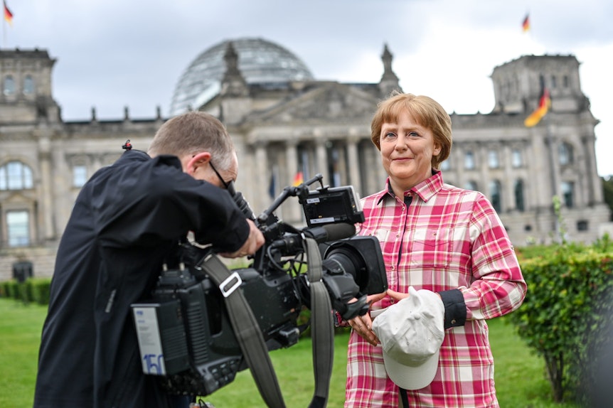 Die Wachsfigur von Bundeskanzlerin Angela Merkel (CDU) aus Madame Tussauds Berlin steht im Freizeitlook mit Rucksack, Basecap vor dem Reichstagsgebäude.