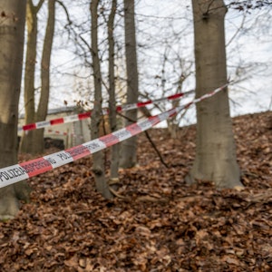 Ein Flatterband der Polizei ist als Absperrung um mehrere Bäume in einem Waldstück gewickelt. Dieses Foto wurde im Juli 2021 aufgenommen.