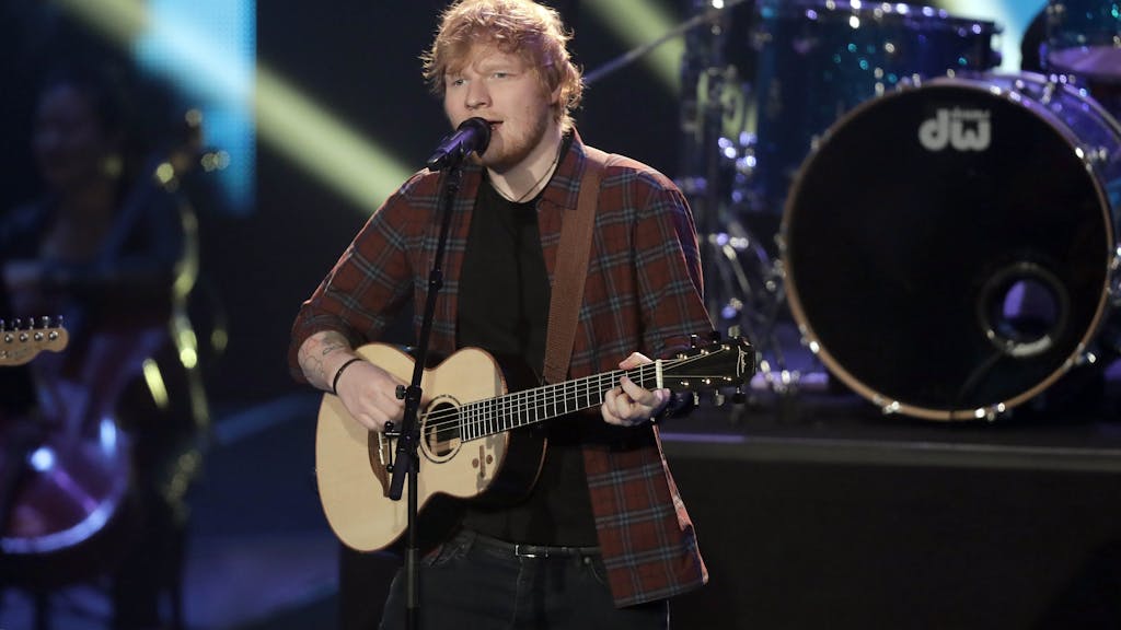 Ed Sheeran singt und spielt Gitarre auf der Bühne.