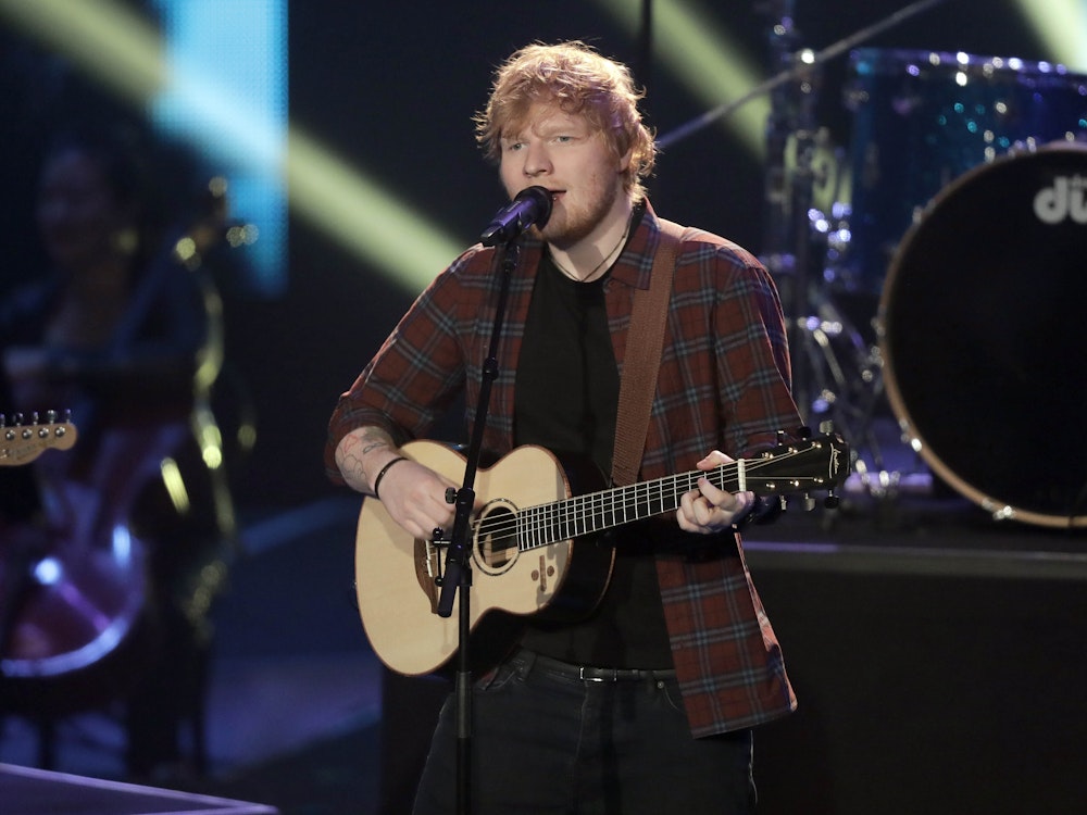 Ed Sheeran singt und spielt Gitarre auf der Bühne.