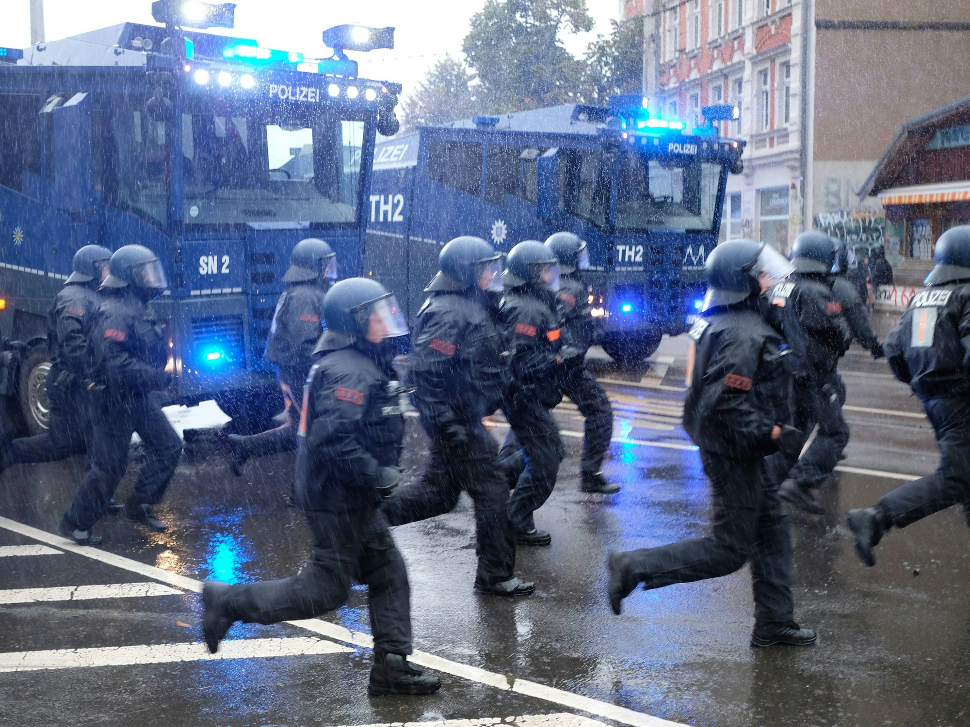 18.09.2021, Sachsen, Leipzig: Polizisten laufen über eine Kreuzung im Stadtteil Connewitz.