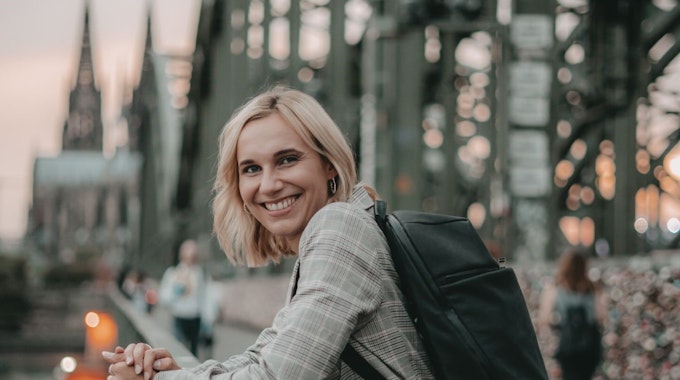 Lena Brabender (26) steht auf einer Brücke, im Hintergrund der Kölner Dom.