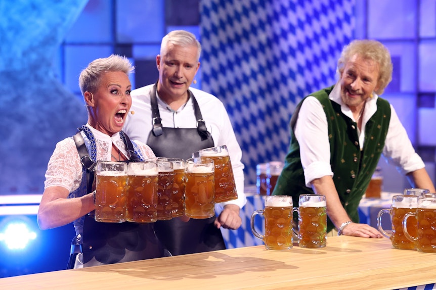 Sonja Zietlow versucht so viele Bierkrüge wie möglich zu stemmen.