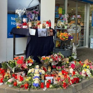 Blumen und Kerzen sind vor der Tankstelle aufgestellt, in der ein 20-jähriger Kassierer mit einem Kopfschuss getötet wurde.